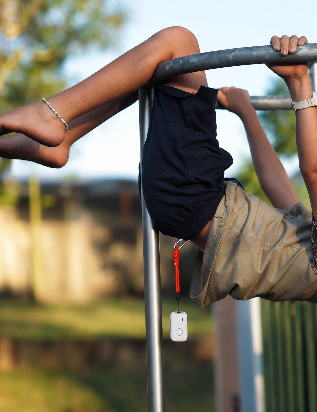 A child on monkey bars at sunset, Sidekick on a red lanyard.